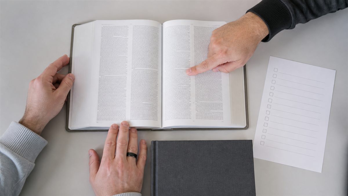 Hands reviewing an open large-print Bible production sample