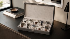 Open watch collection display box with six organized watches.