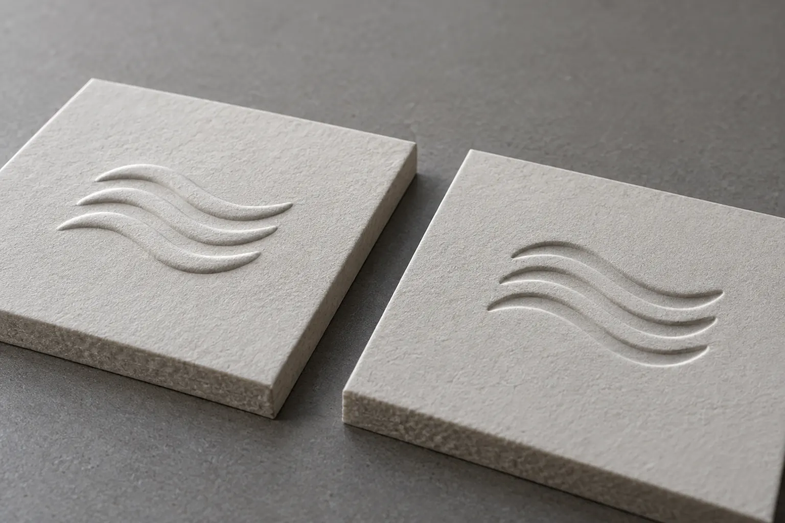 Raised and recessed versions of the same wave motif on two paperboard cover samples