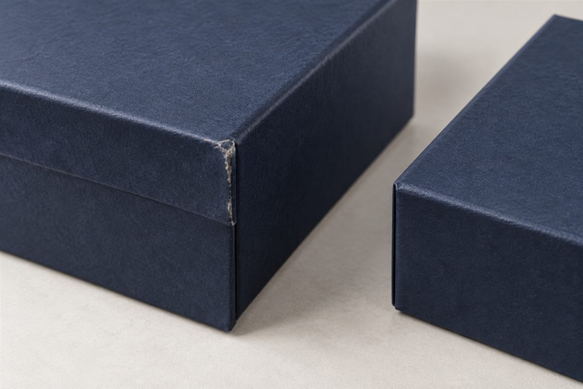 Scuffed and intact paper-wrapped box edges under inspection