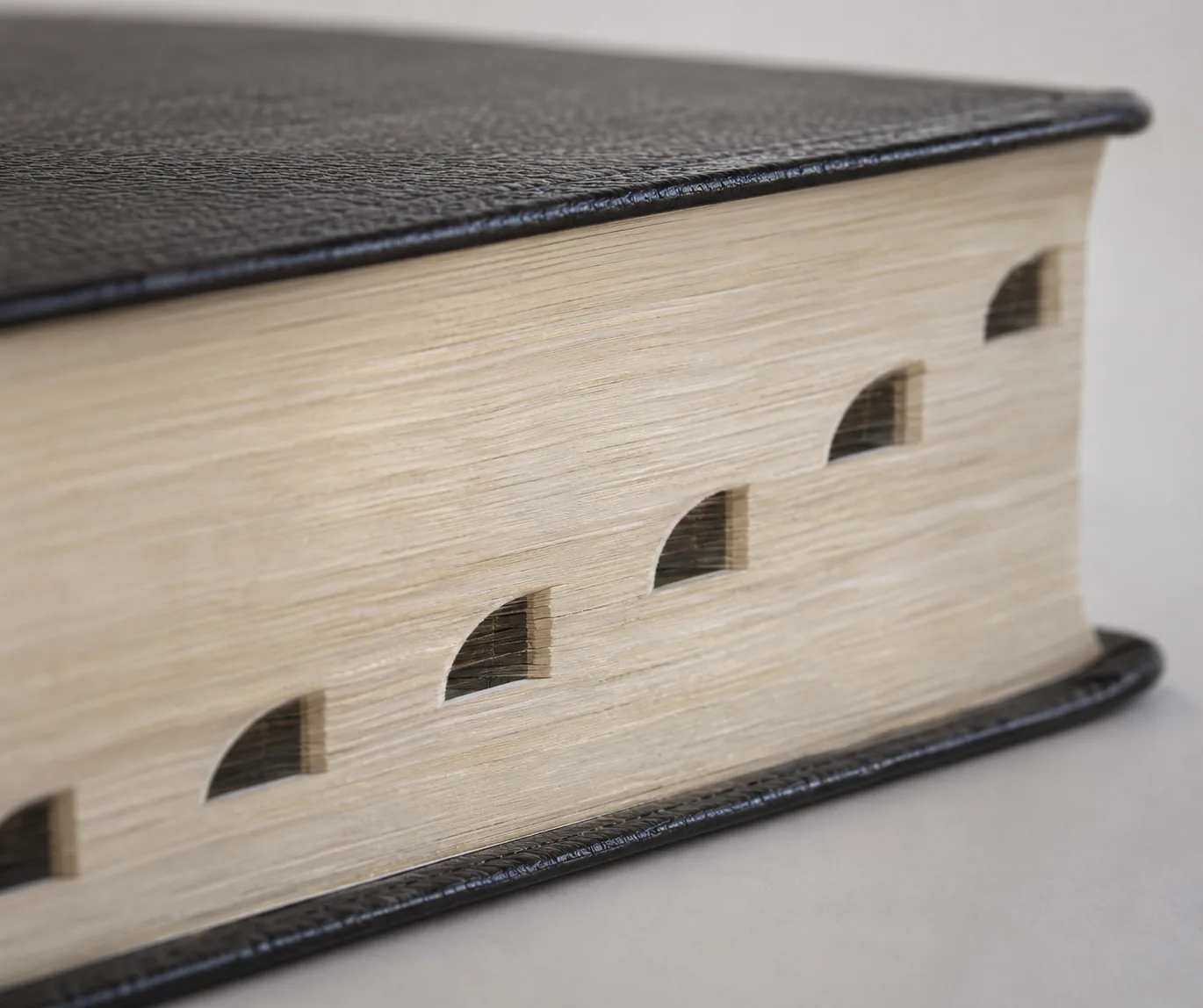 Semicircular thumb-index notches cut into the page edge of a dark-covered Bible